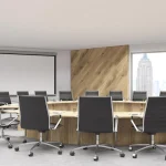 A modern conference room featuring a round wooden table with sleek black swivel chairs arranged around it. The room includes large windows with a cityscape view and a wooden accent wall that adds warmth to the space. A projector screen is mounted on the opposite wall, showcasing the room's functionality for meetings and presentations. The design reflects a professional and sophisticated atmosphere.