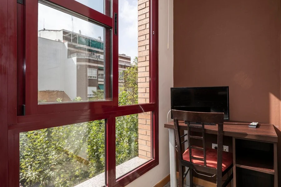 Comfortable hotel room with a work desk, chair, TV, and a scenic view from the window.